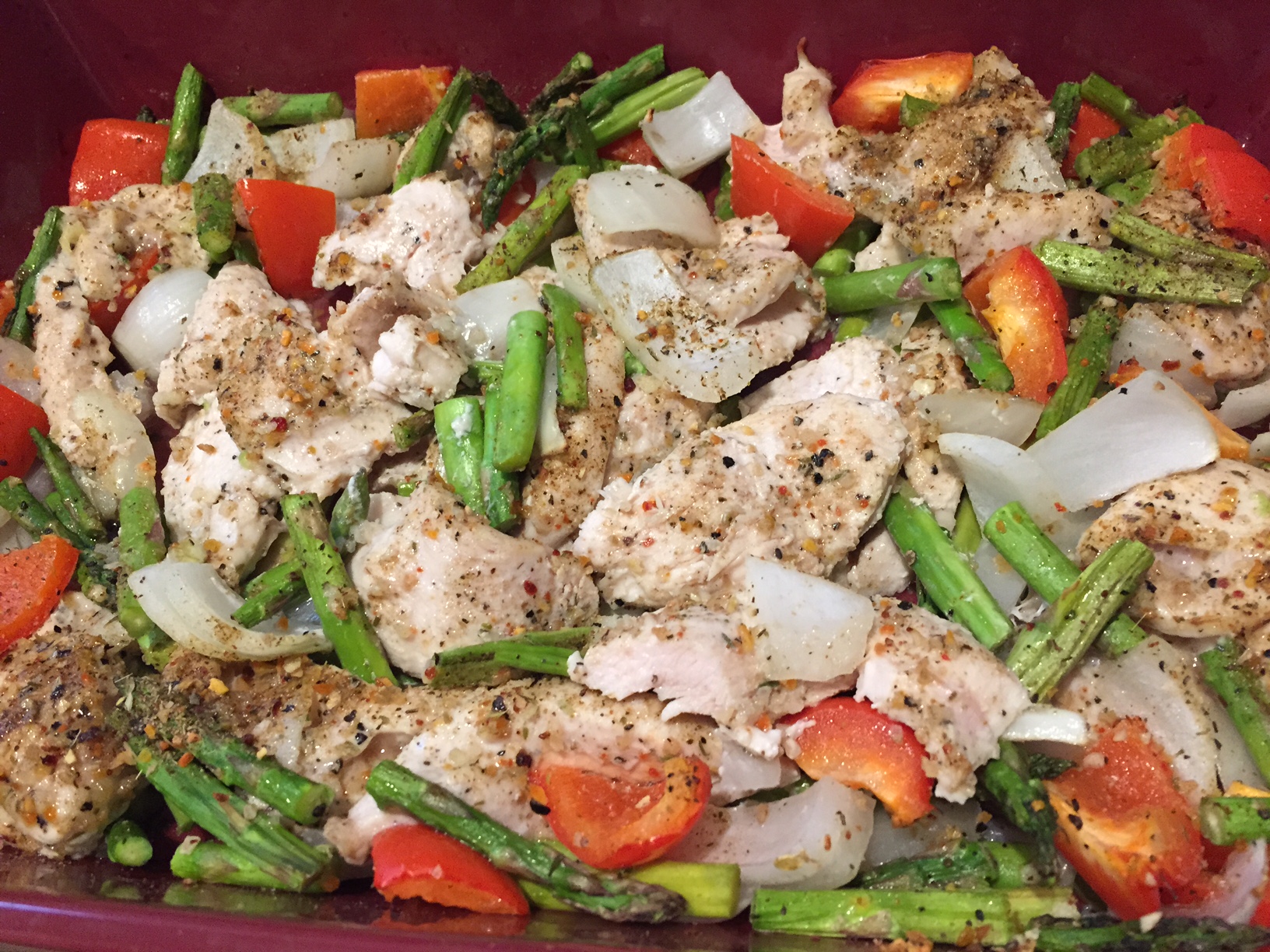 easy chicken bake dinner in a red casserole pan with green beans, peppers, onions