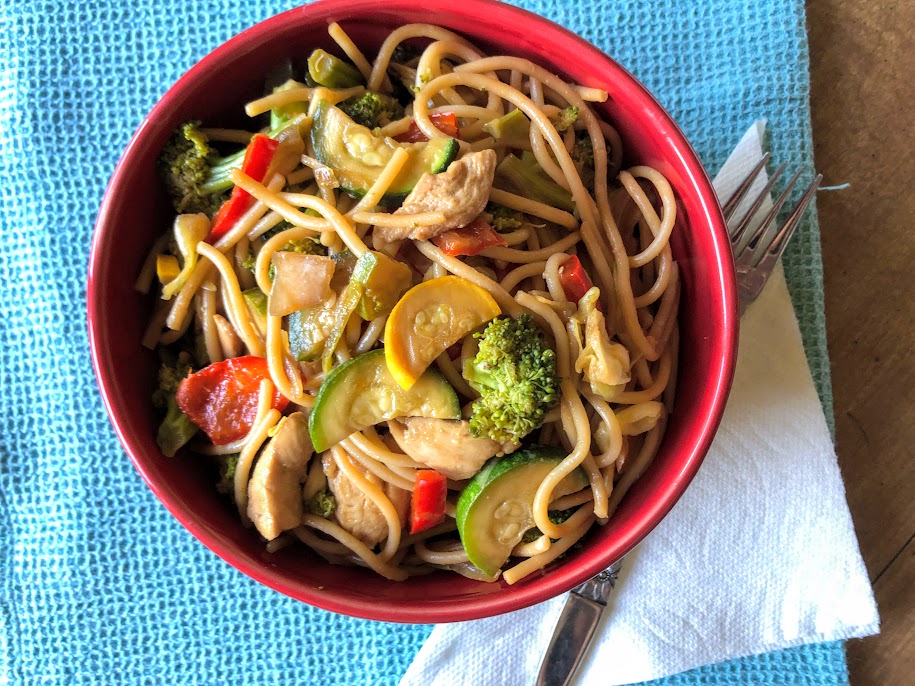 chicken lo mein in a red bowl with napkin
