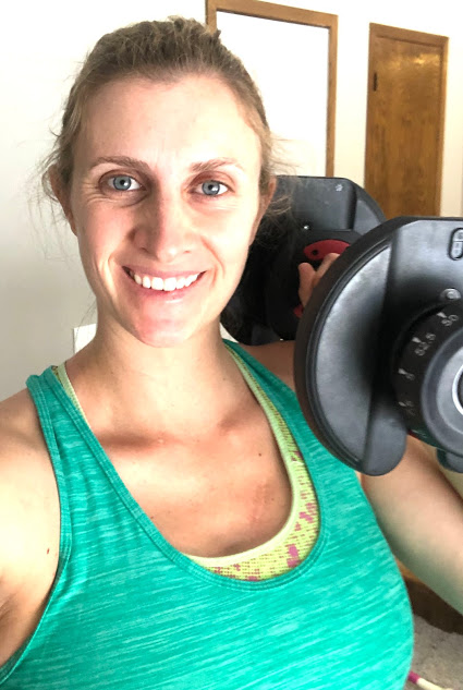Woman smiling holding a dumbbell after an at home workout
