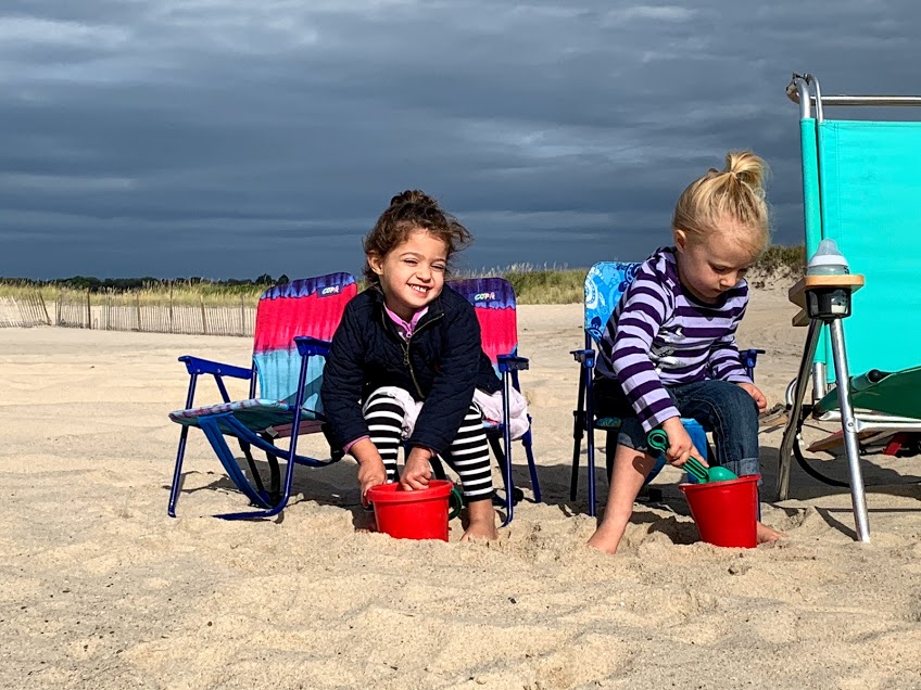 Two girls sitting in beach chairs playing with sand buckets