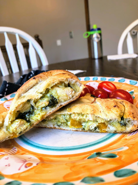 chicken pesto calzones cut in half on an orange plate