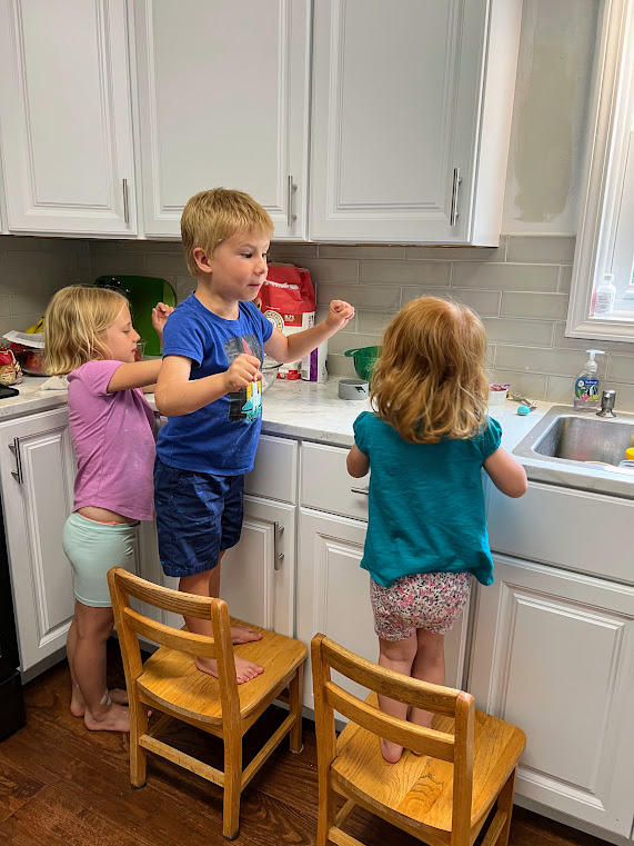 Three kids at the kitchen counter making playdoh