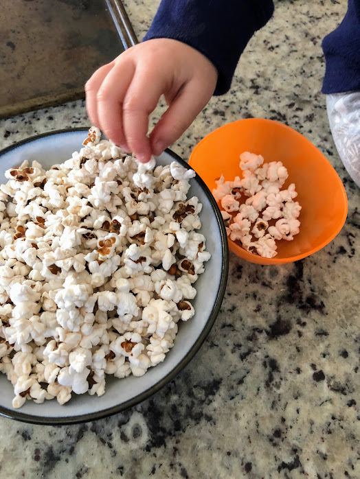 bowl of popcorn with child's hand reaching for some