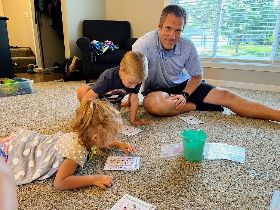 Father and two kids playing bingo on the floor together