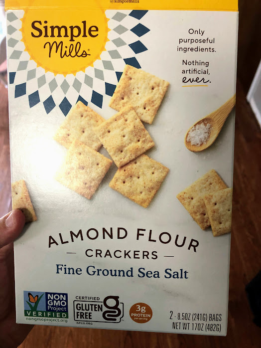 box of Simple Mills Almond Flour Crackers in hand for a road trip snack