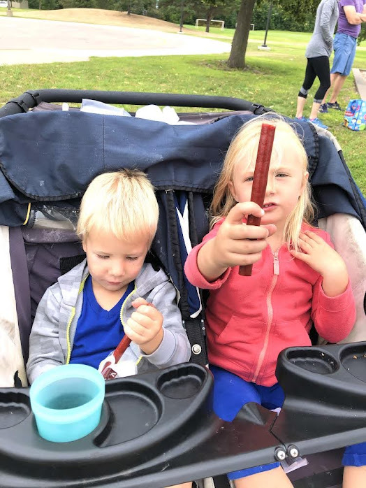Two kids in a stroller eating jerky