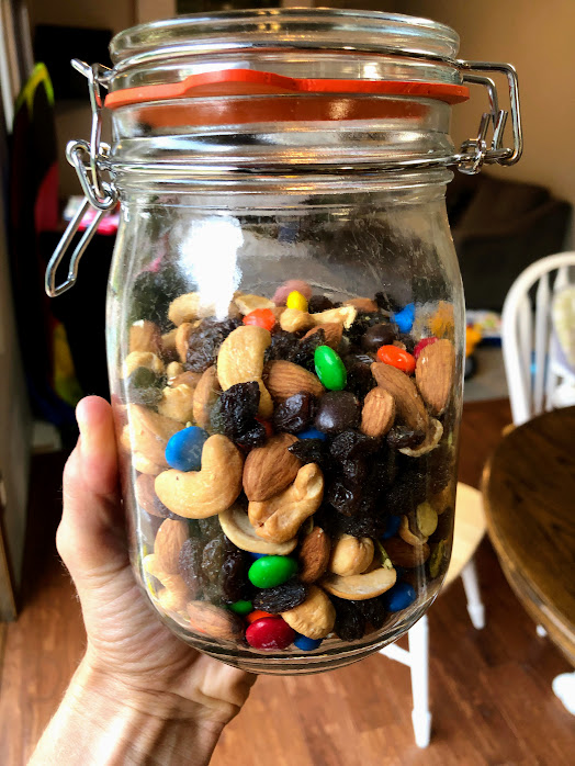 homemade trail mix in a glass container held up with a hand