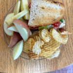 sandwich on toasted bread with sliced apple and chips
