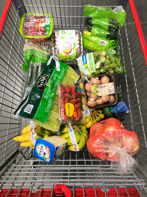 Costco grocery cart with greens in bulk